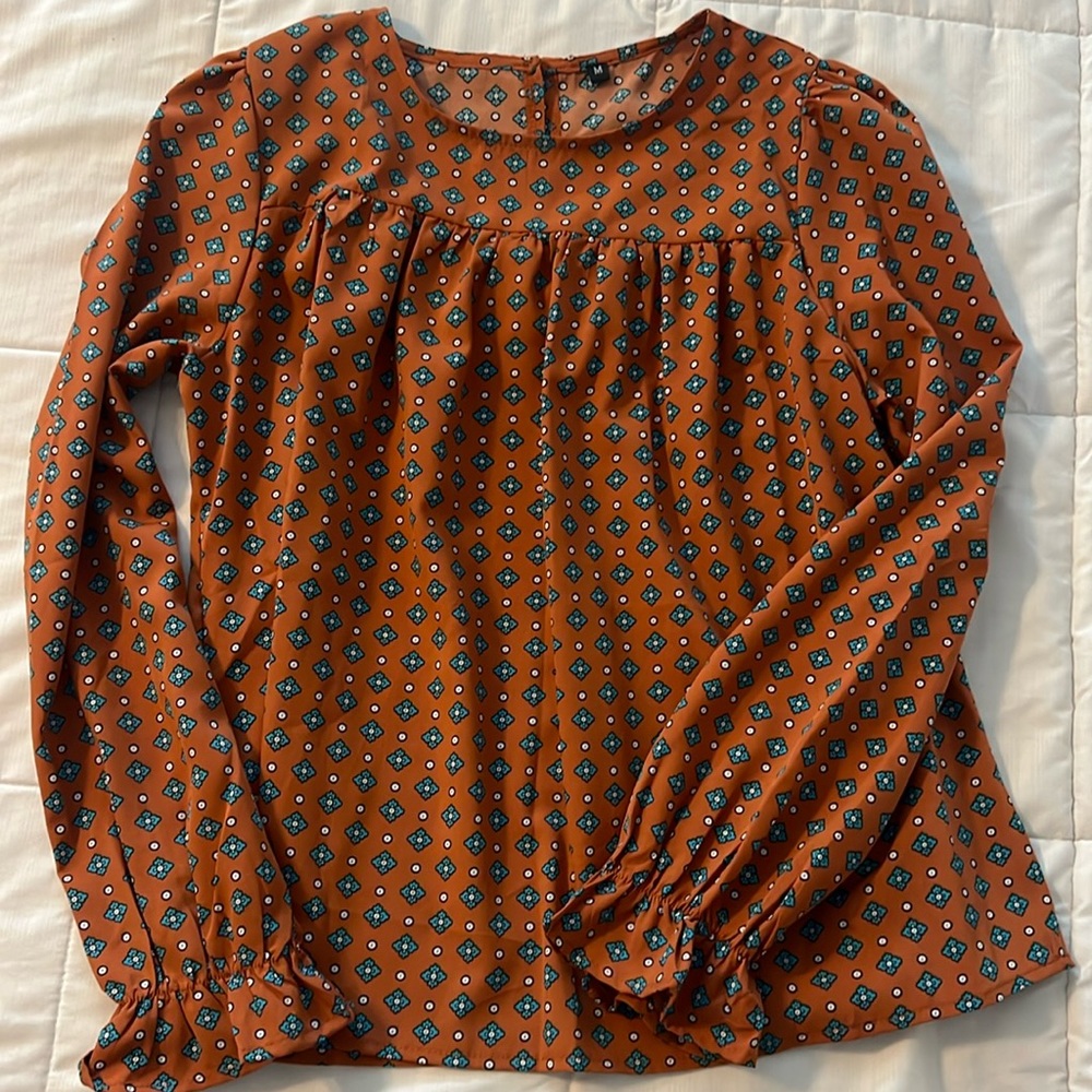 Long sleeved, silk top with a ruffled sleeve detail.